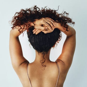person styling their curly hair from behind